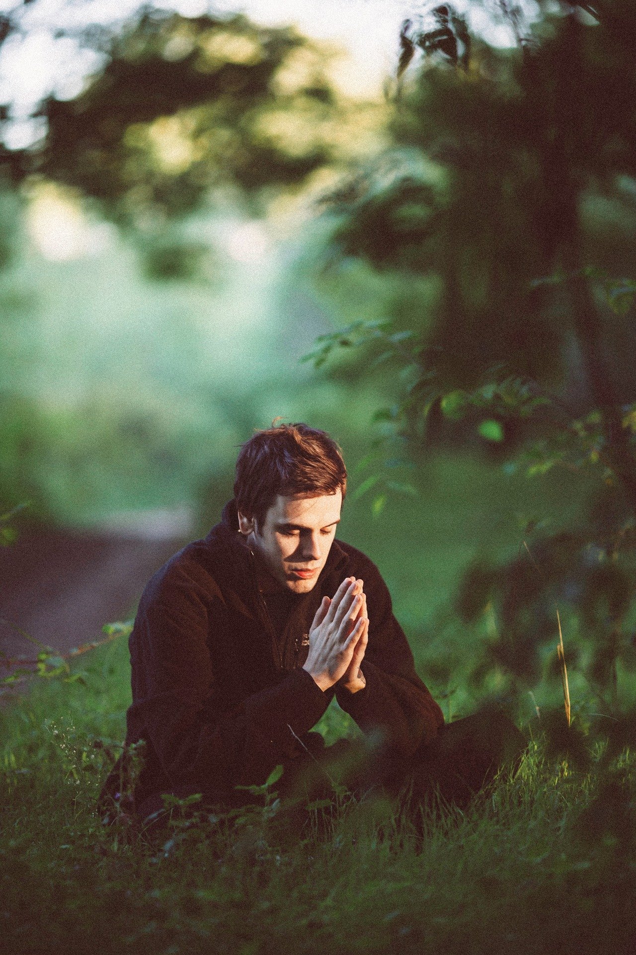 Homem orando sentado em jardim