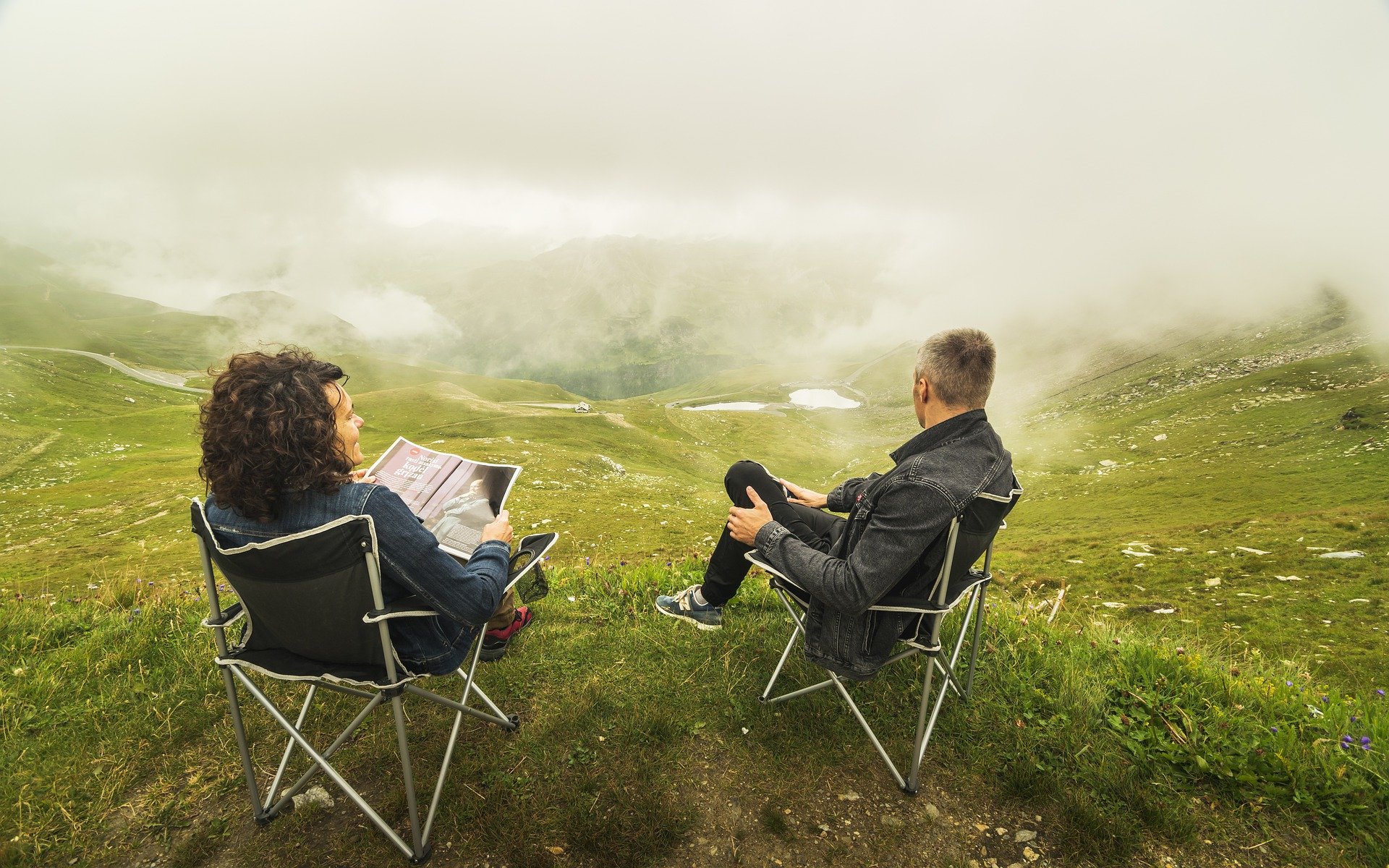 Homem e mulher sentados em campo de vegetação em um dia nublado