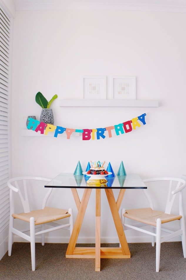 Faixa de feliz aniversário escrito em inglês pendurada em parede acima de mesa