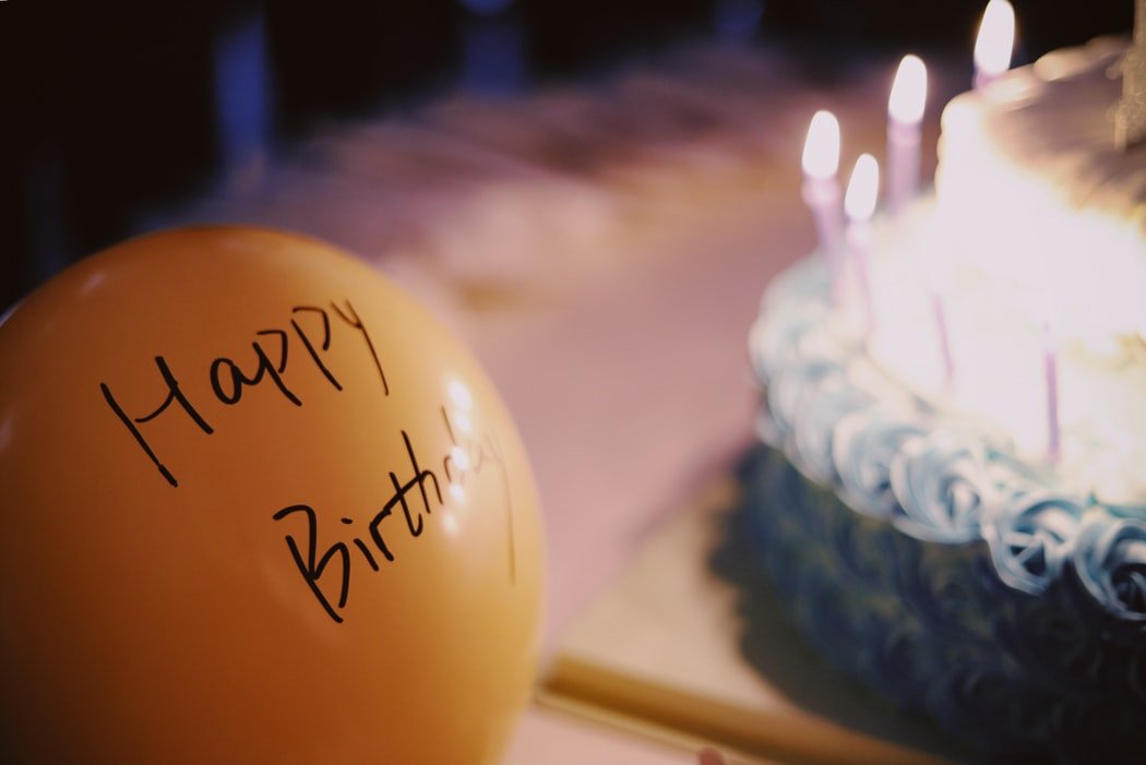 Bolo de aniversário e balão escrito feliz aniversário em inglês