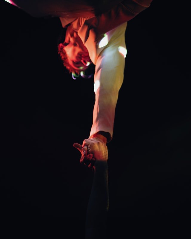 Artistas circenses segurando as mãos durante apresentação trapezista