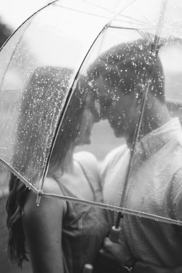 Casal abraçados embaixo de guarda chuva