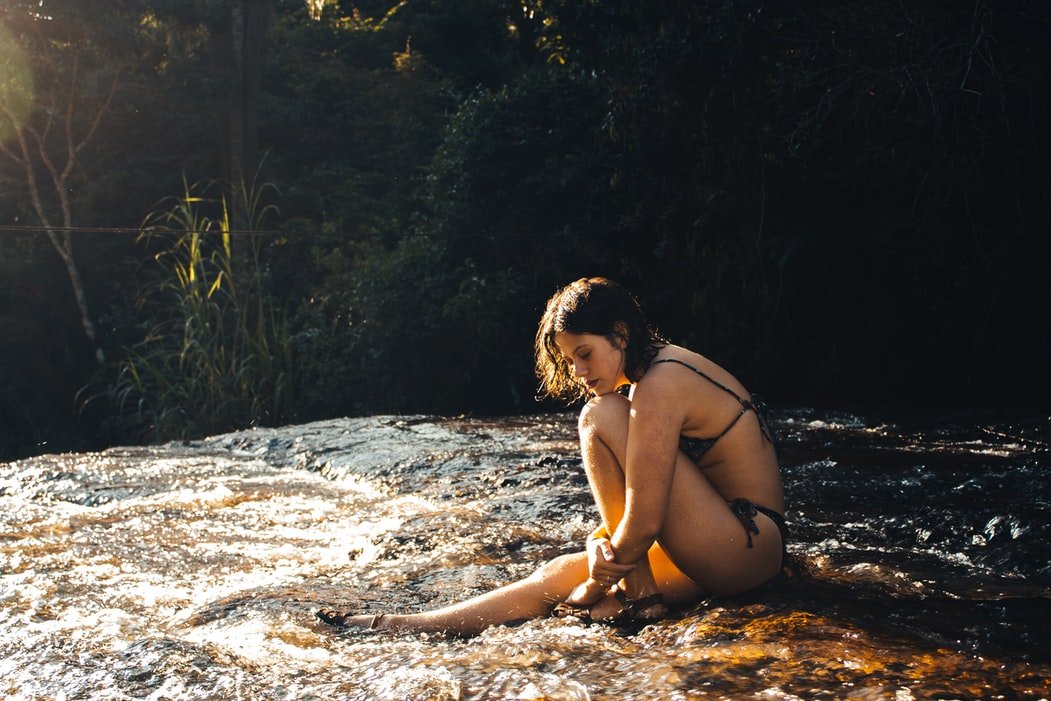 Mulher sentada em pedra de cachoeira