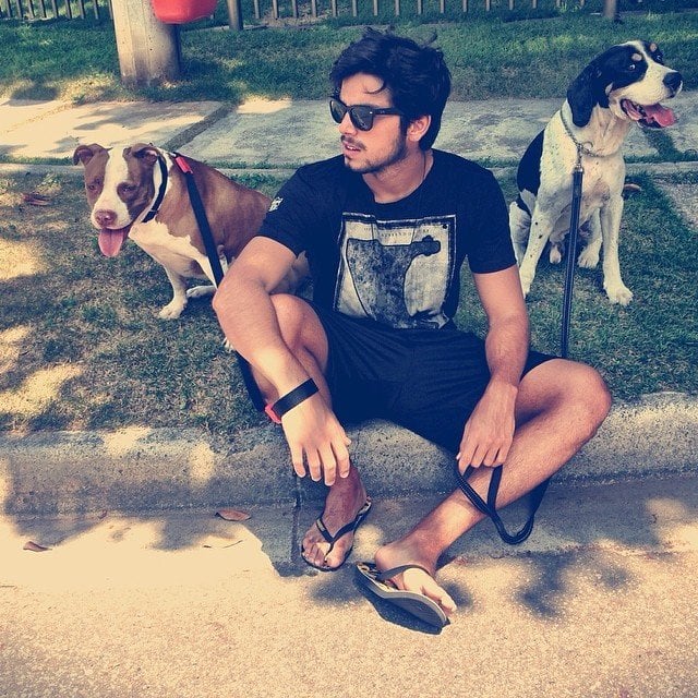 Rodrigo Simas ao lado de seus cachorros em calçada.