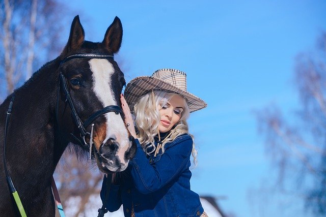 Mulher loira com chapéu e mãos em cavalo