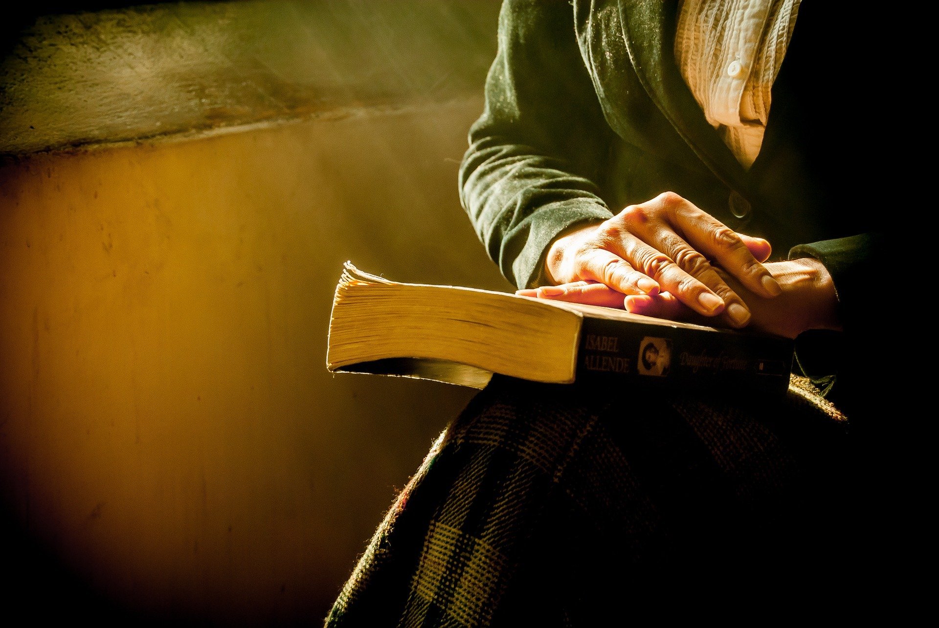 Mulher orando com as mãos apoiadas sobre a bíblia