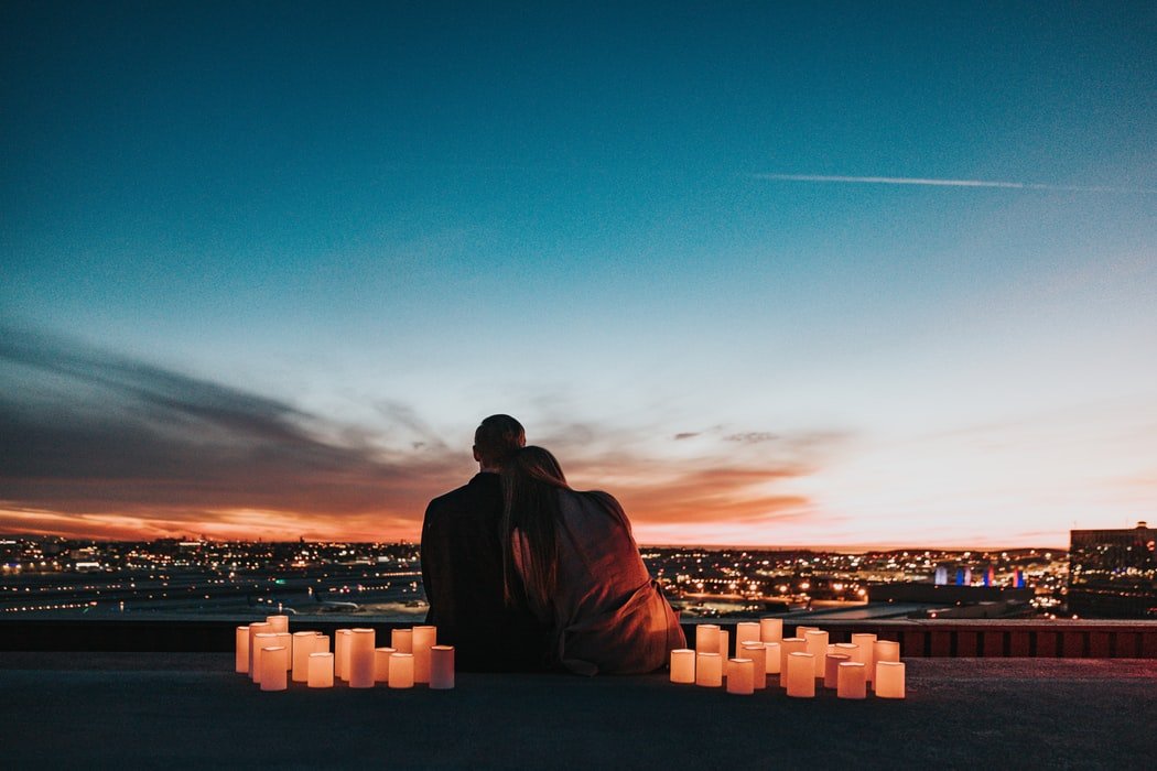 Casal se abraçando sentados observando paisagem de cidade