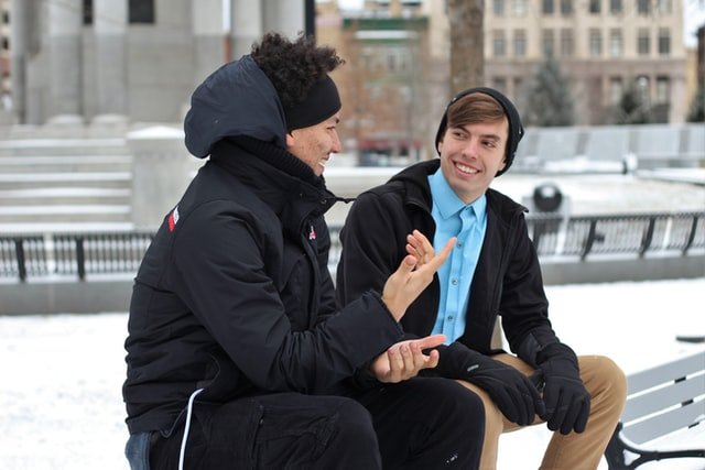 Dois homens sentados em um banco conversando