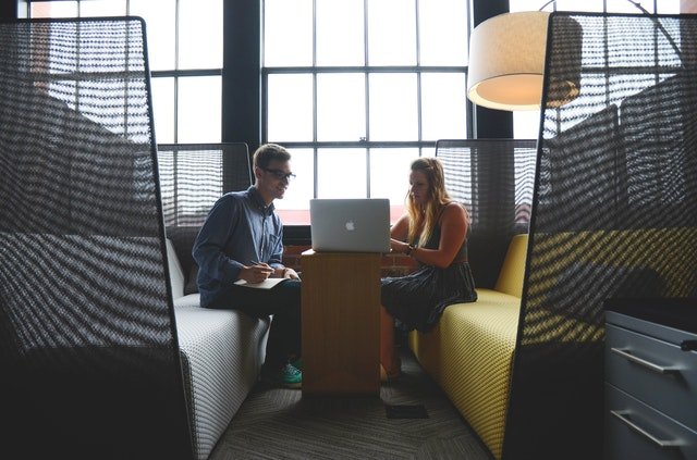 Pexels/Startup Stock Photos Homem e mulher sentados em frente a um computador