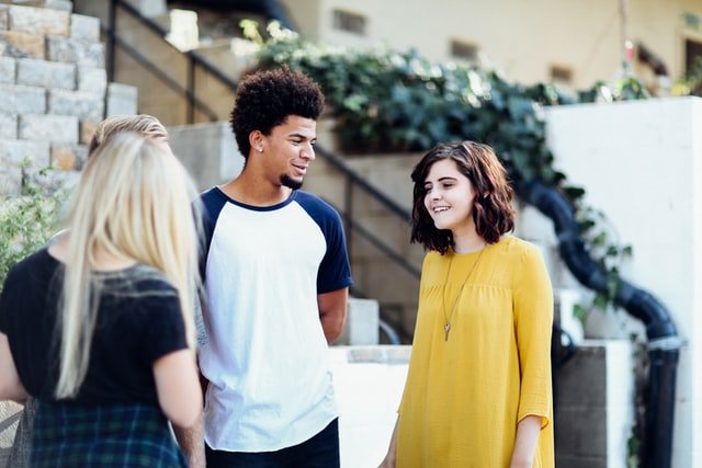 Um homem olha para uma mulher, que conversa com outra a sua frente