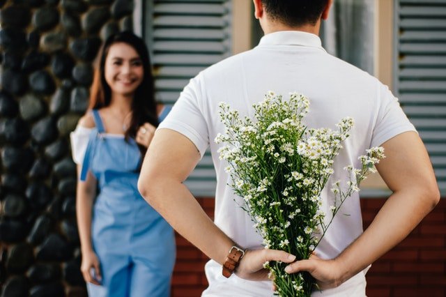 Homem escondendo um buquê de flores da mulher a sua frente