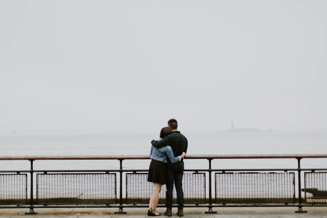 Homem e mulher abraçados olhando o mar