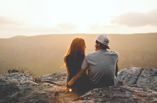 Homem e mulher sentados em topo de montanha