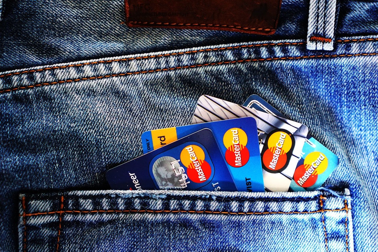 Detalhe de um bolso de calça jeans com quatro cartões de crédito se sobrepondo.