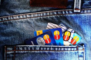 Pexels/Pixabay Detalhe de um bolso de calça jeans com quatro cartões de crédito se sobrepondo.