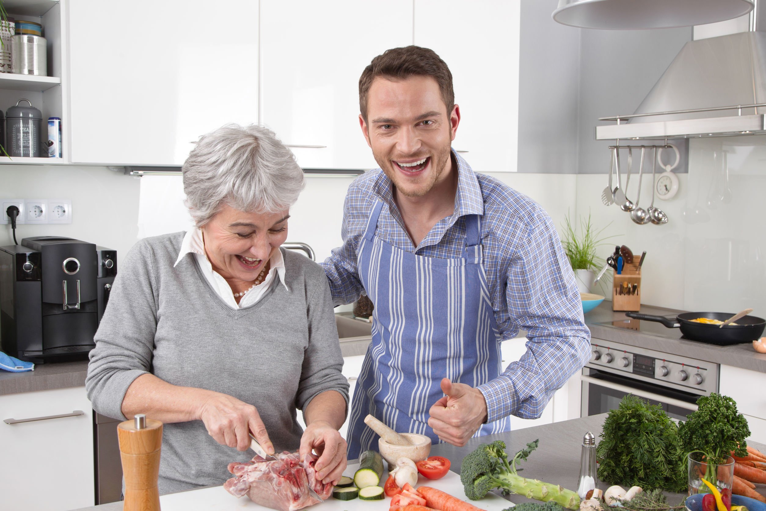 Senhora e homem sorrindo enquanto cozinham
