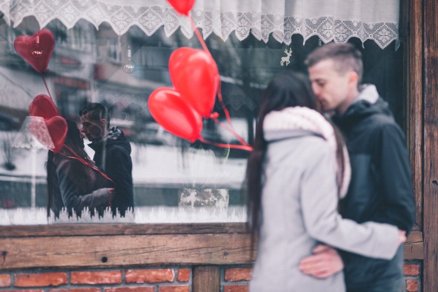 Casal se abraçando e balões em formato de coração