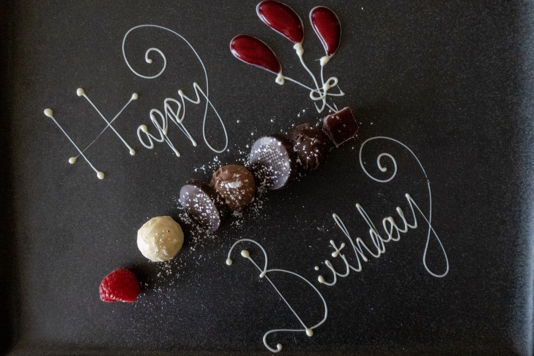 Feliz aniversário escrito em inglês com chocolate branco em badeja de doces