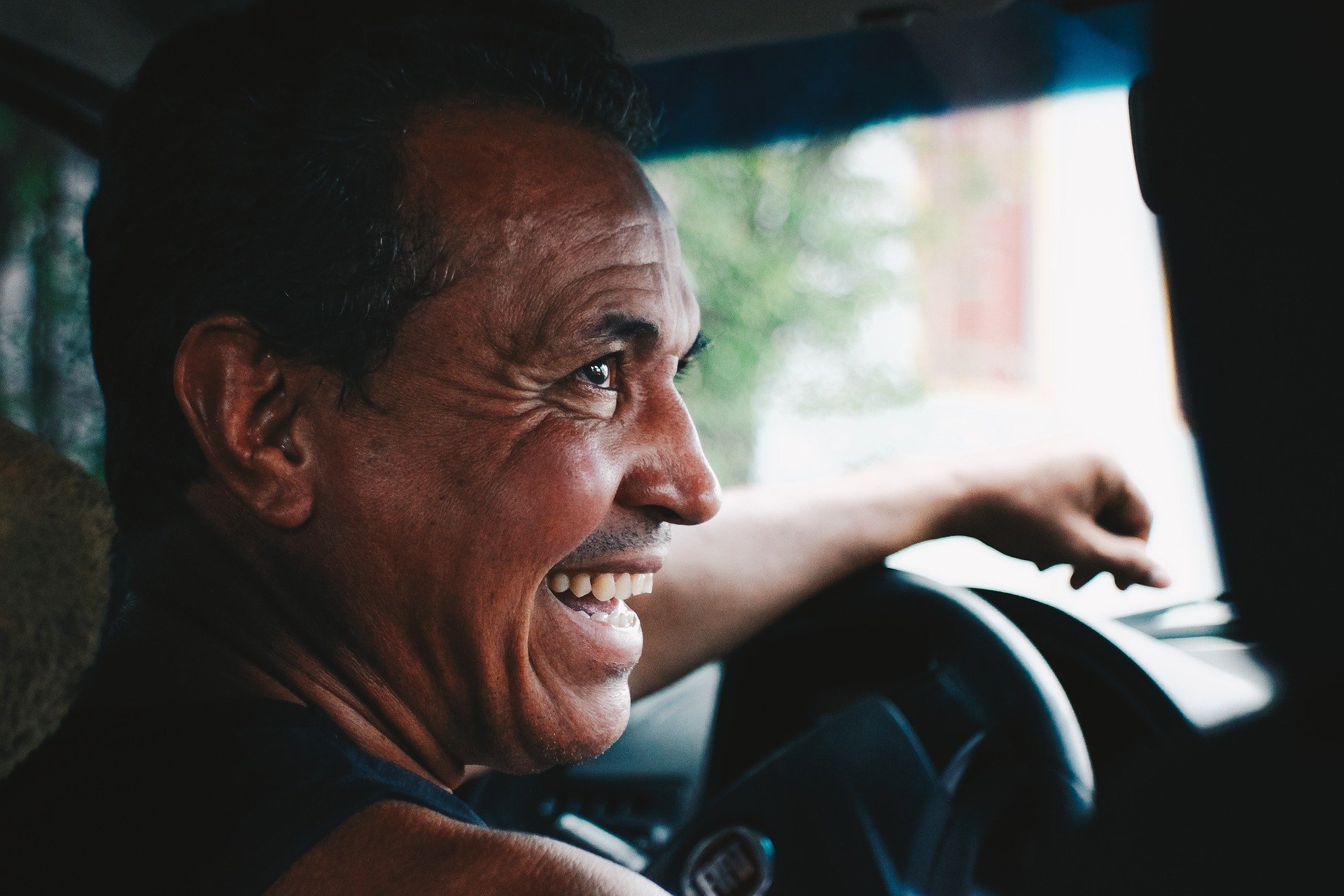 Homem rindo enquanto dirige carro