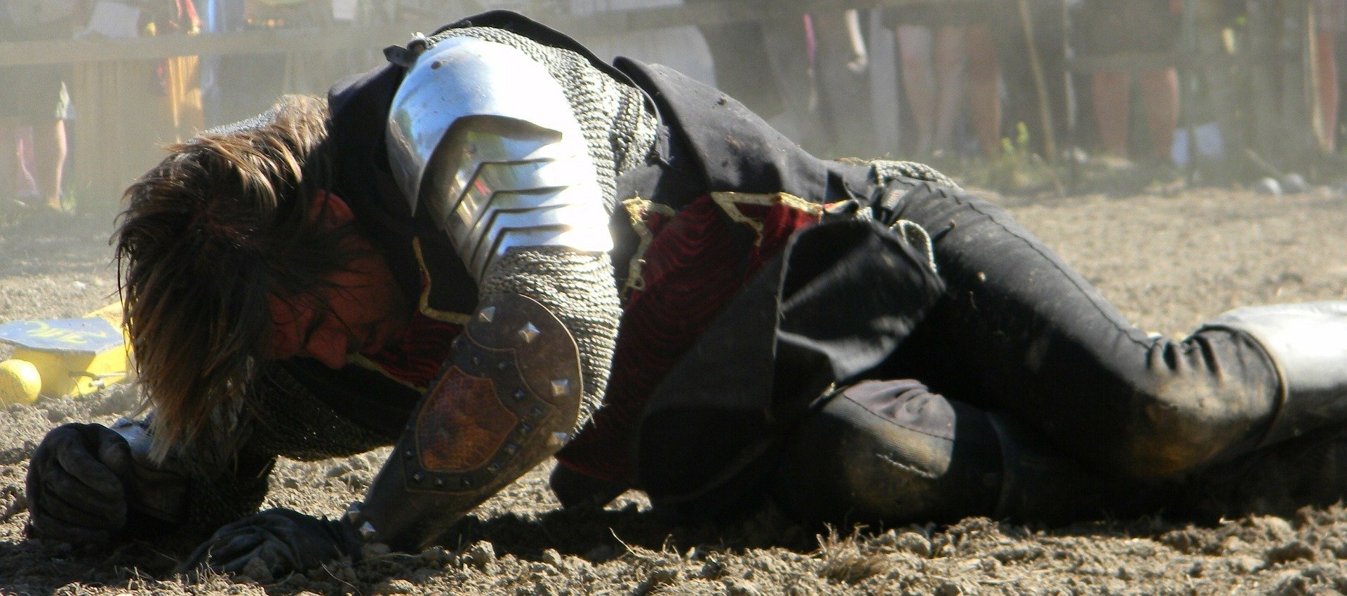 Homem usando roupas medievais, caído no chão, se levantando