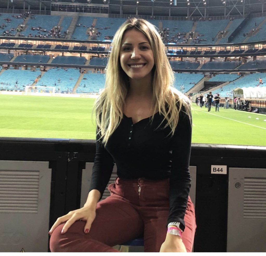 Mulher sorrindo sentada em estádio de futebol/ Bárbara Coelho