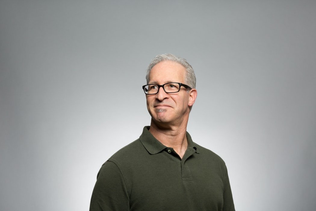Homem de meia idade, com os cabelos grisalhos, usando óculos de grau, sorrindo com expressão de orgulho