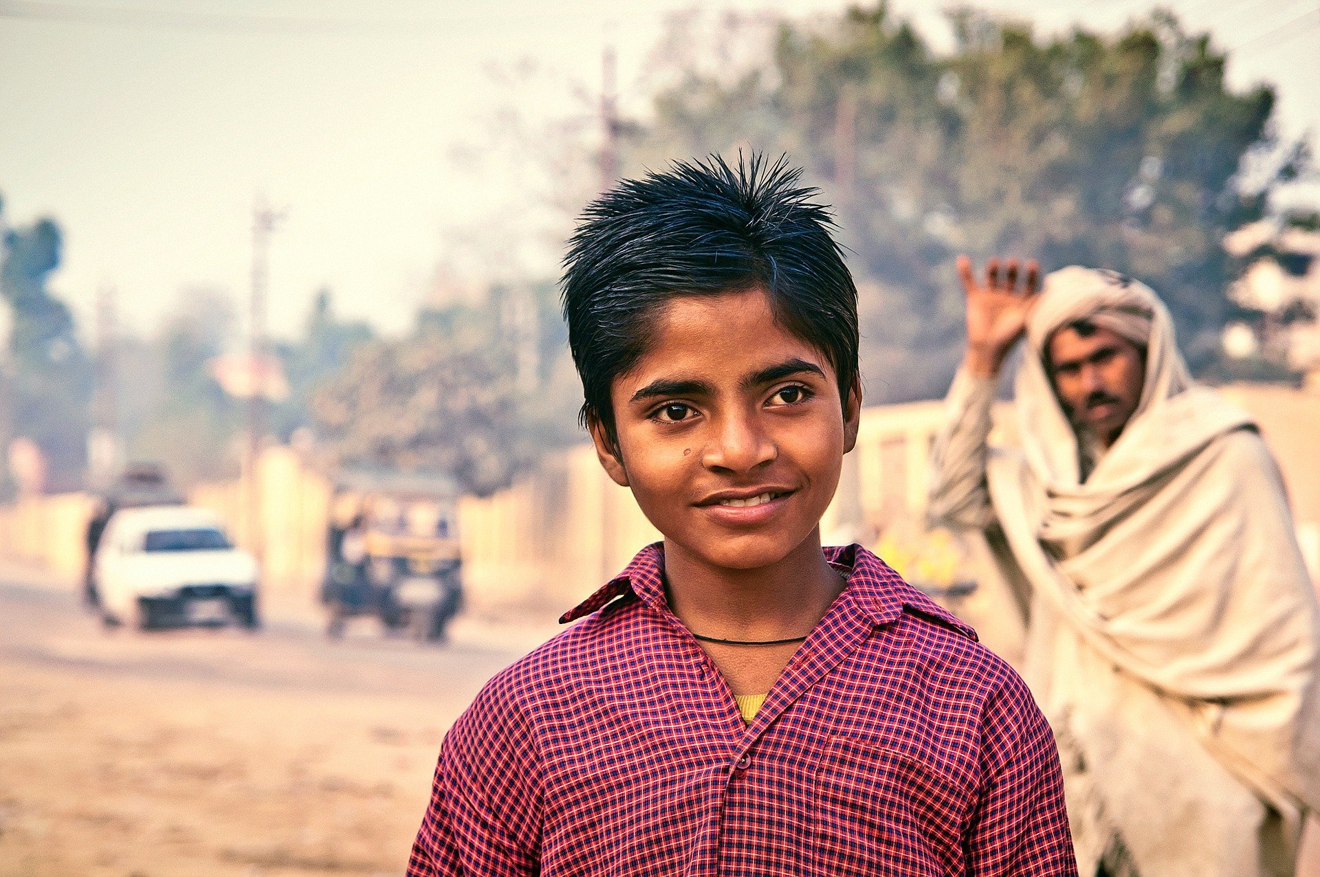 Menino indiano, sorrindo, em pé no meio da rua