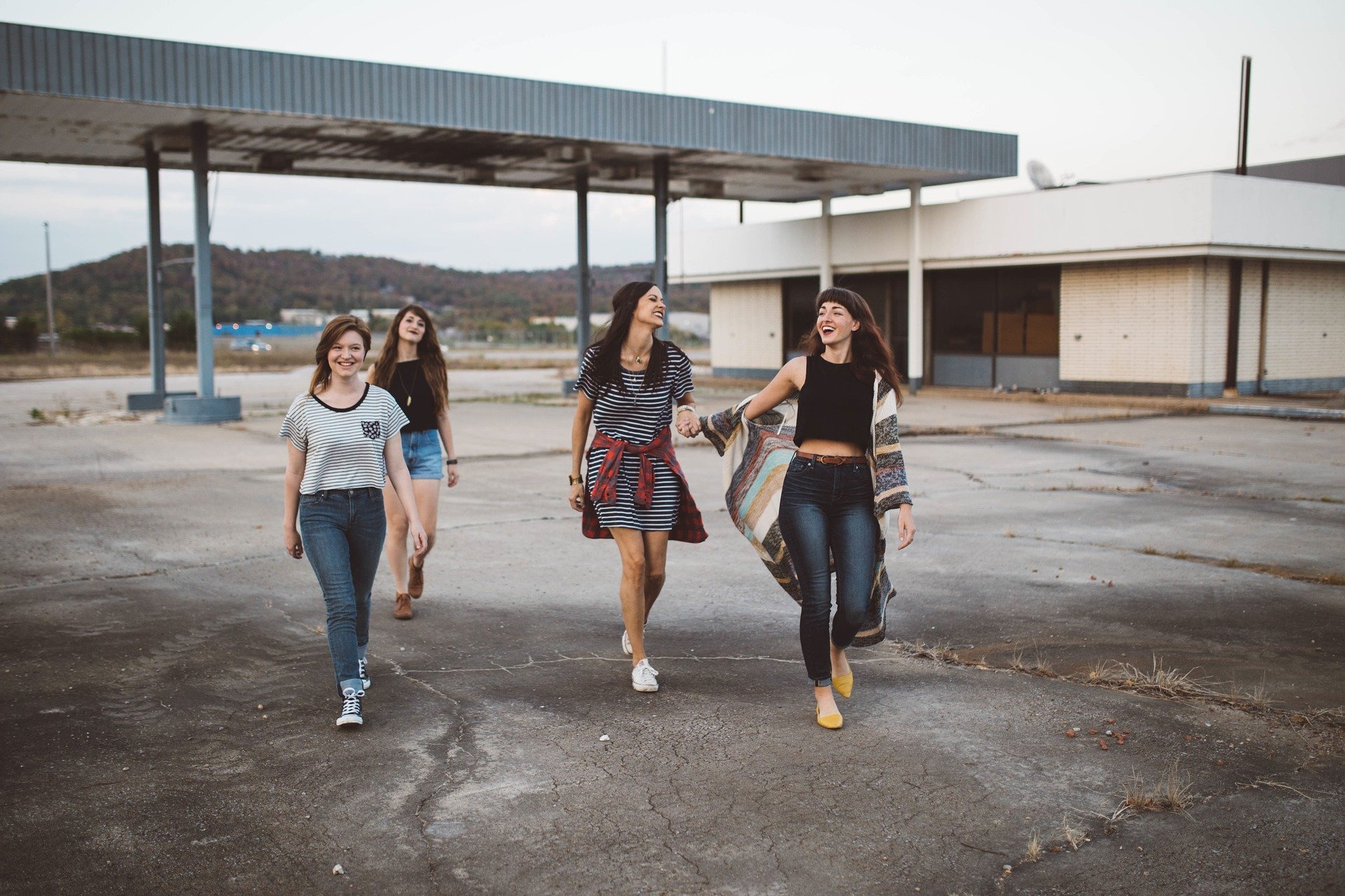 Grupo de quatro mulheres caminhando e dando risadas