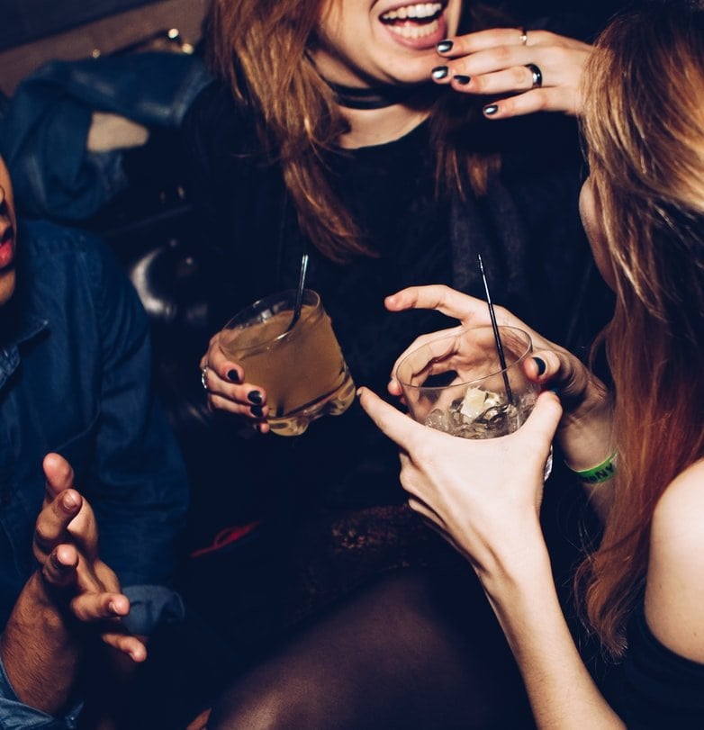 Mulheres em festa sorrindo segurando bebida