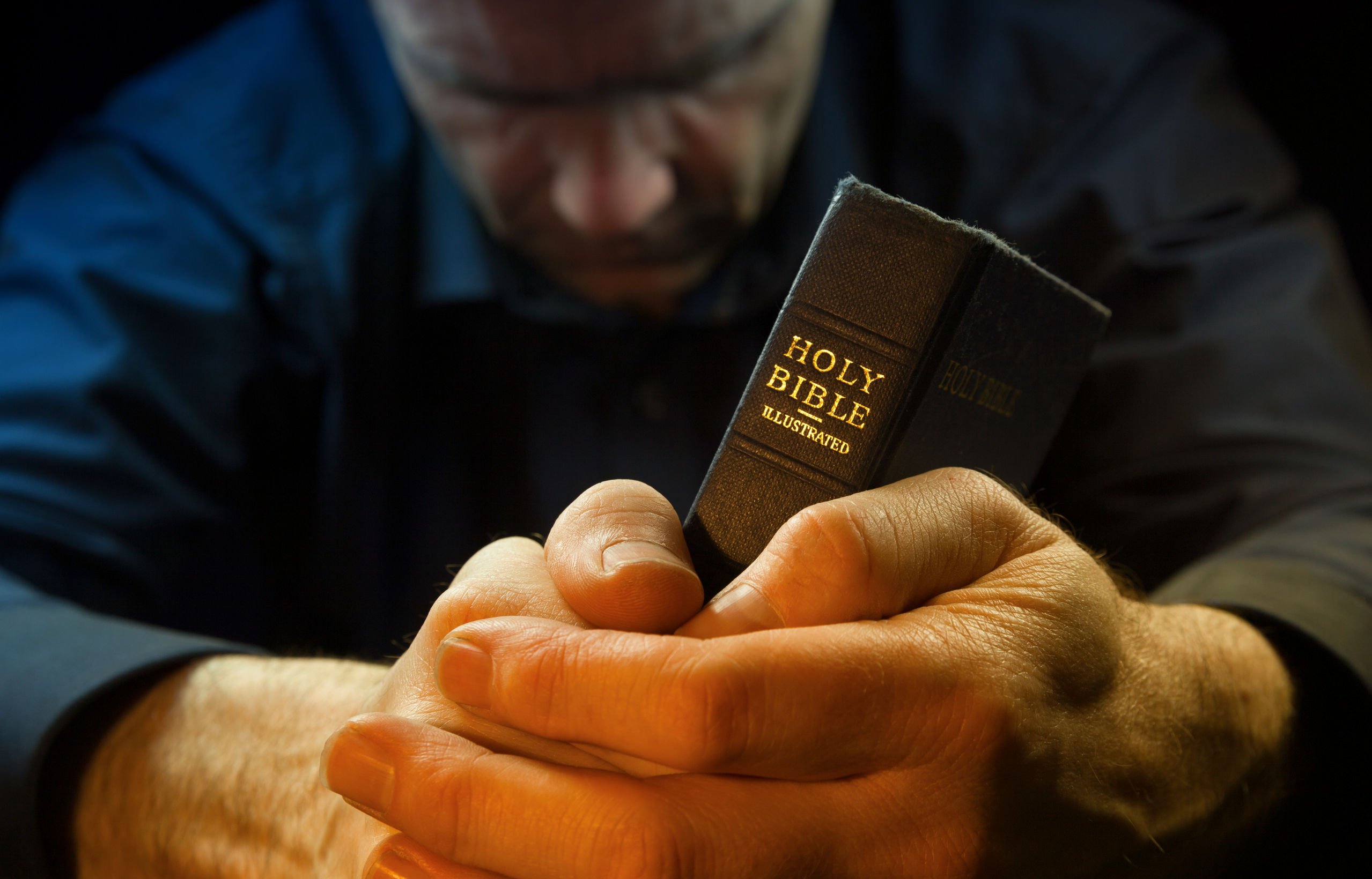 Homem orando segurando bíblia