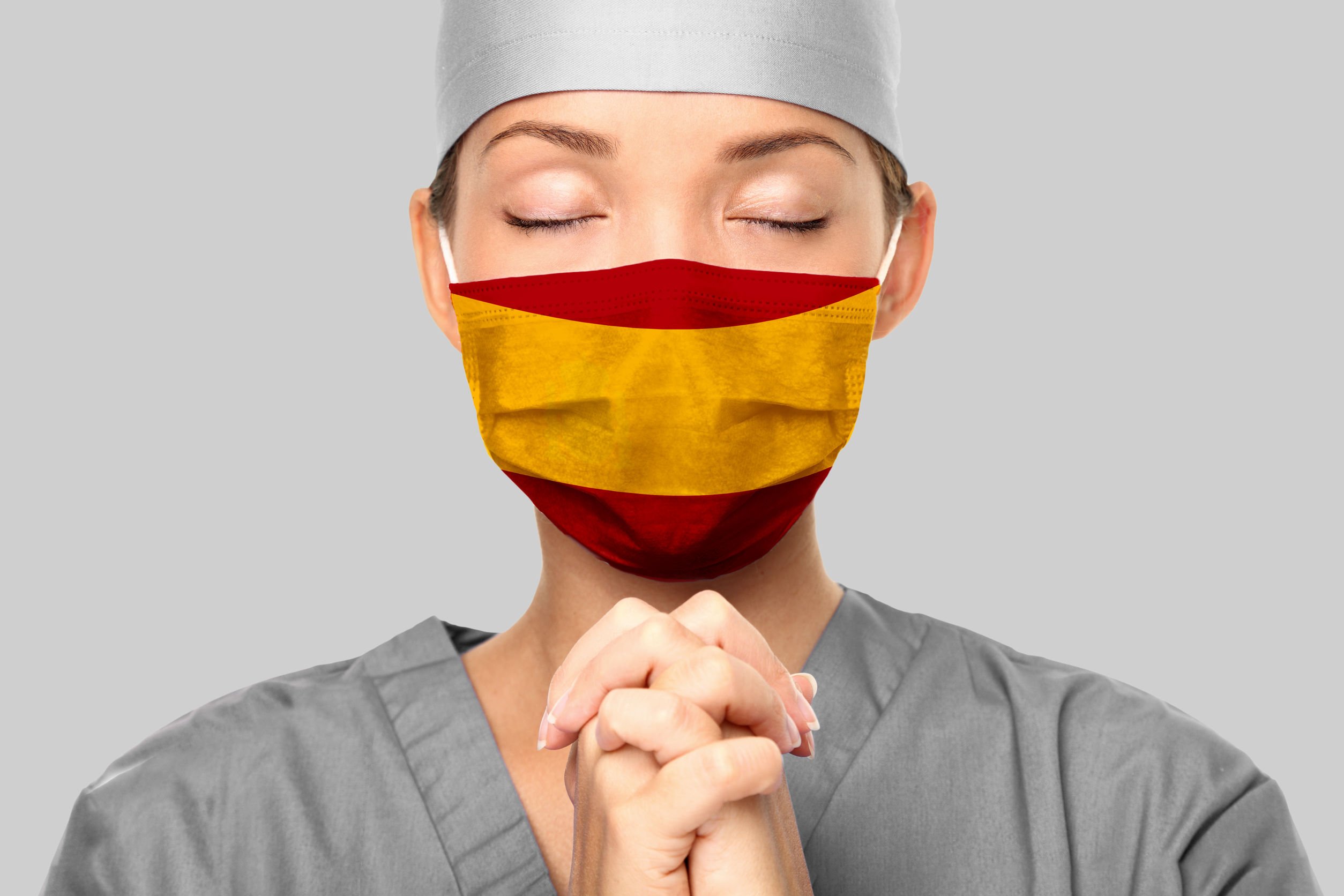 Médica usando roupas cirúrgicas e máscara, orando