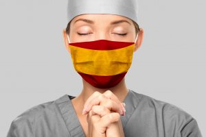 maridav /123RF Médica usando roupas cirúrgicas e máscara, orando