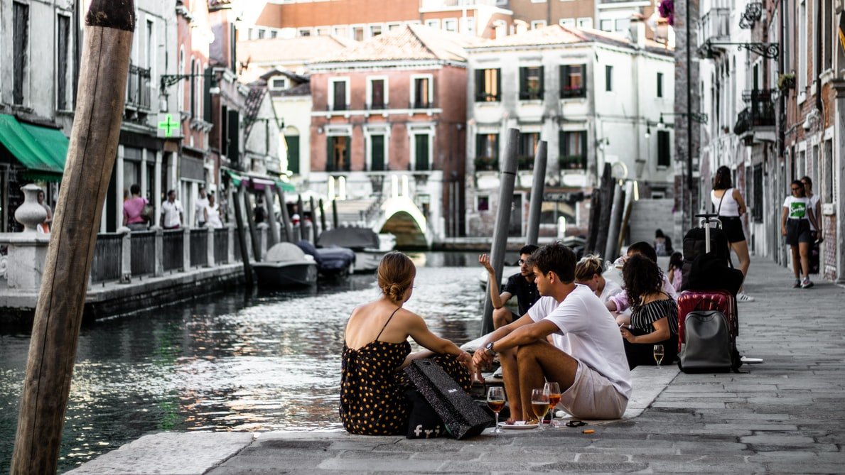 Amigos jantando ao ar livre em beira de canal de rio em Veneza