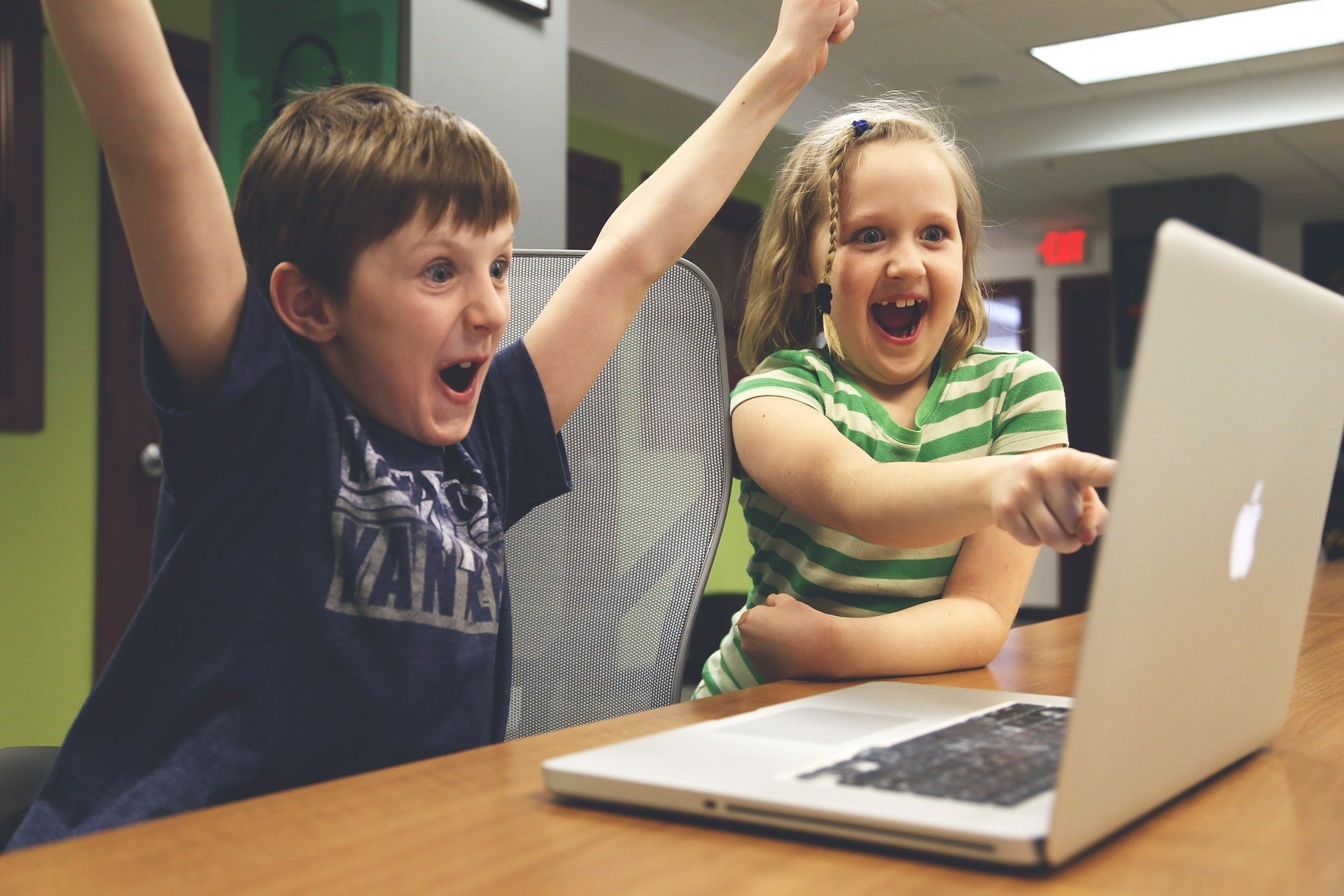 Menina e menino olhando para computador e comemorando