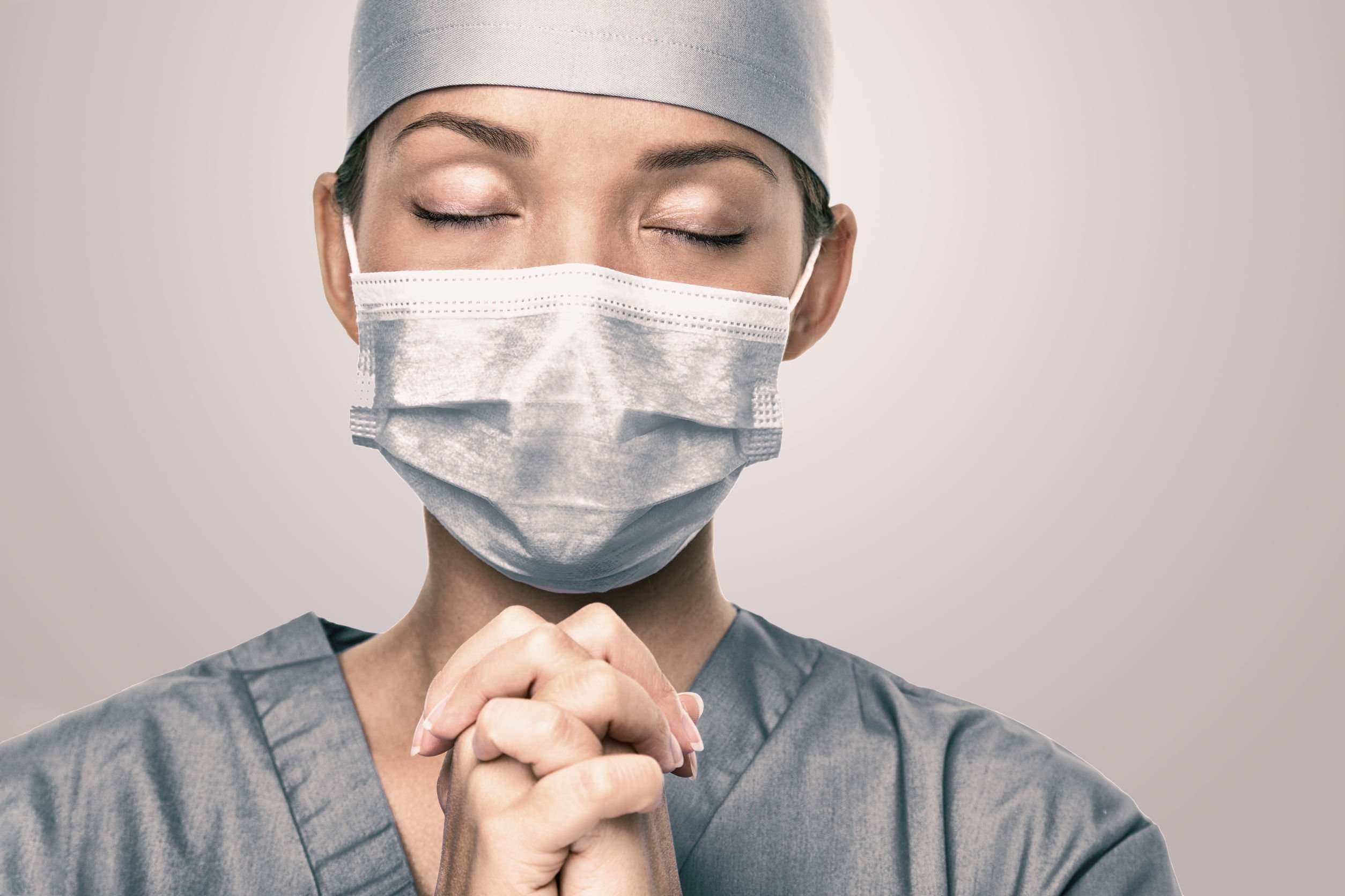 Enfermeira com mãos juntas orando
