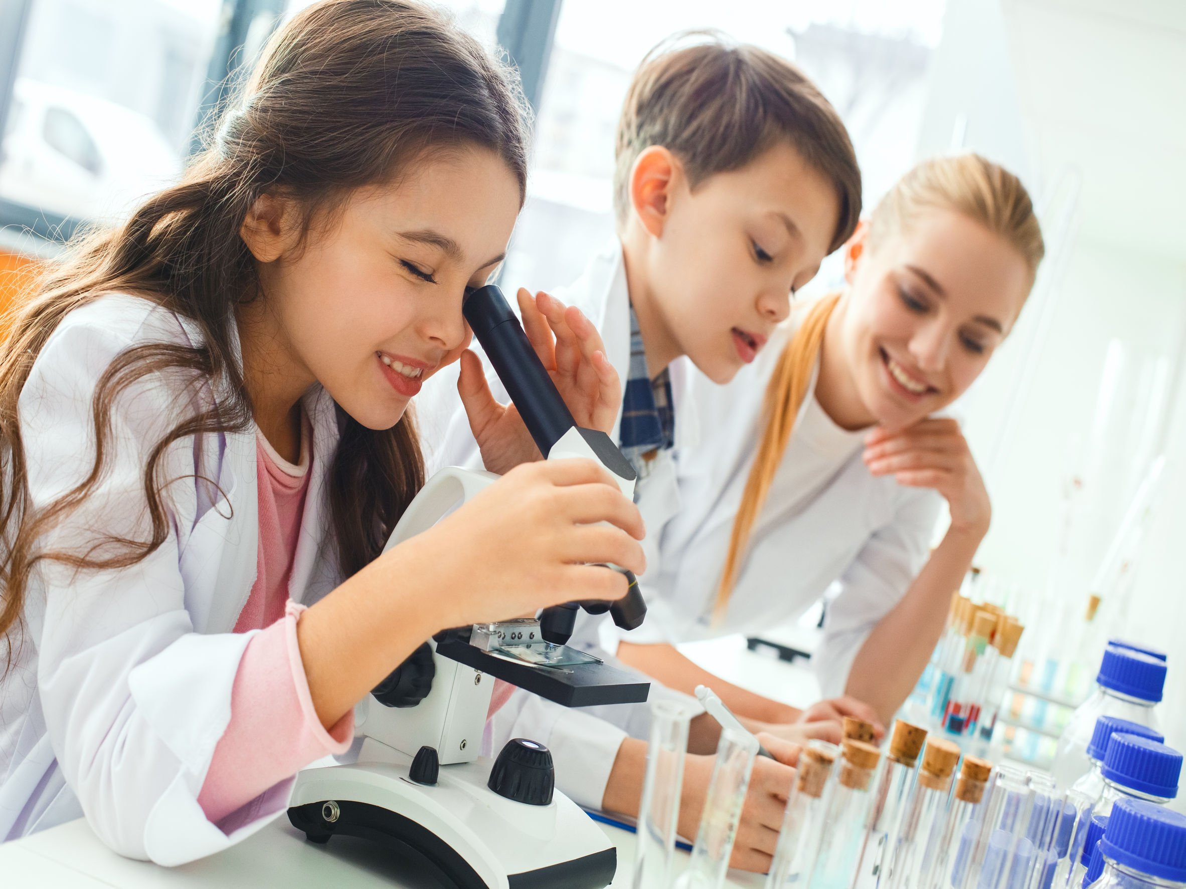 Crianças olhando em microscópio enquanto brincam em laboratório