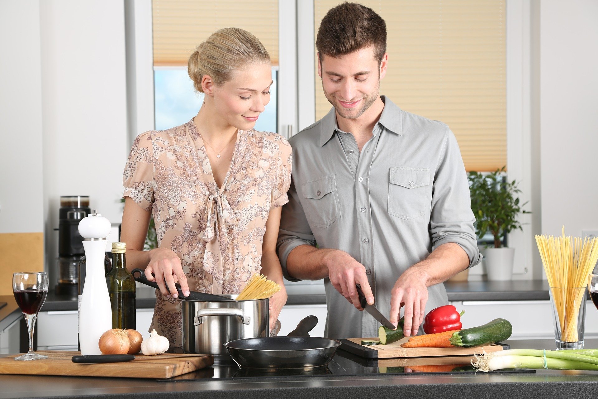 Homem e mulher cozinhando e cortando alimentos