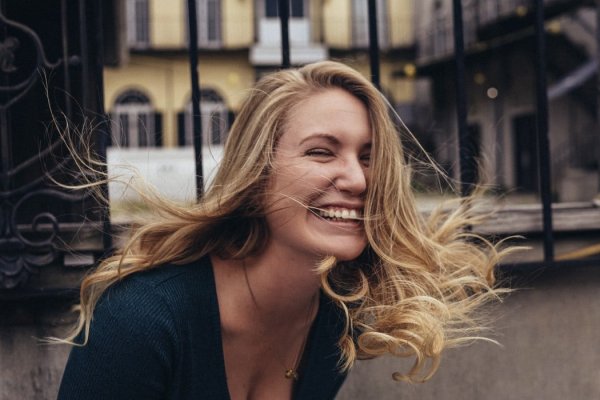 Jeryd Gillum/ Unsplash Mulher sorrindo feliz, com os cabelos ao vento