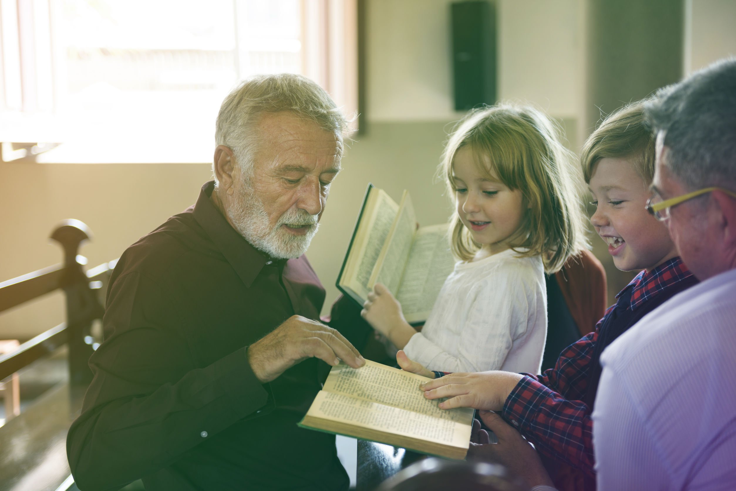 Pastor lendo bíblia para homem e crianças