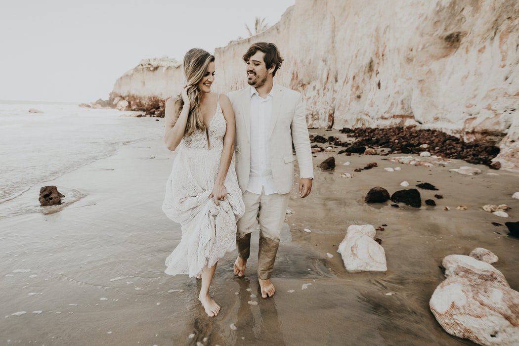 Homem e mulher sorrindo caminhando em praia