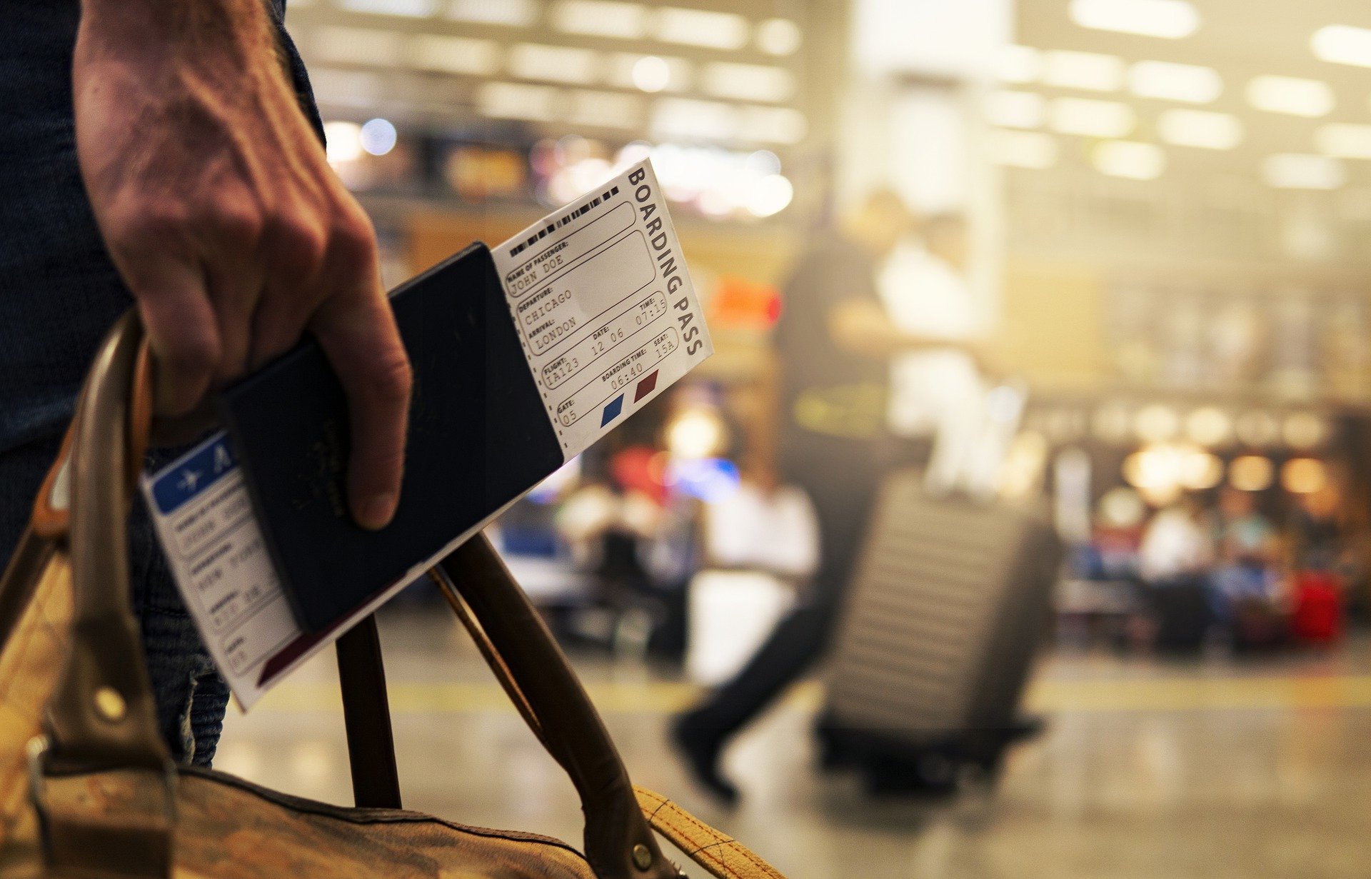 Homem segurando passaporte e mala de viagem