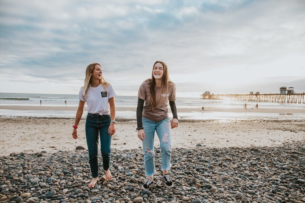 Mulheres sorrindo caminhando em praia