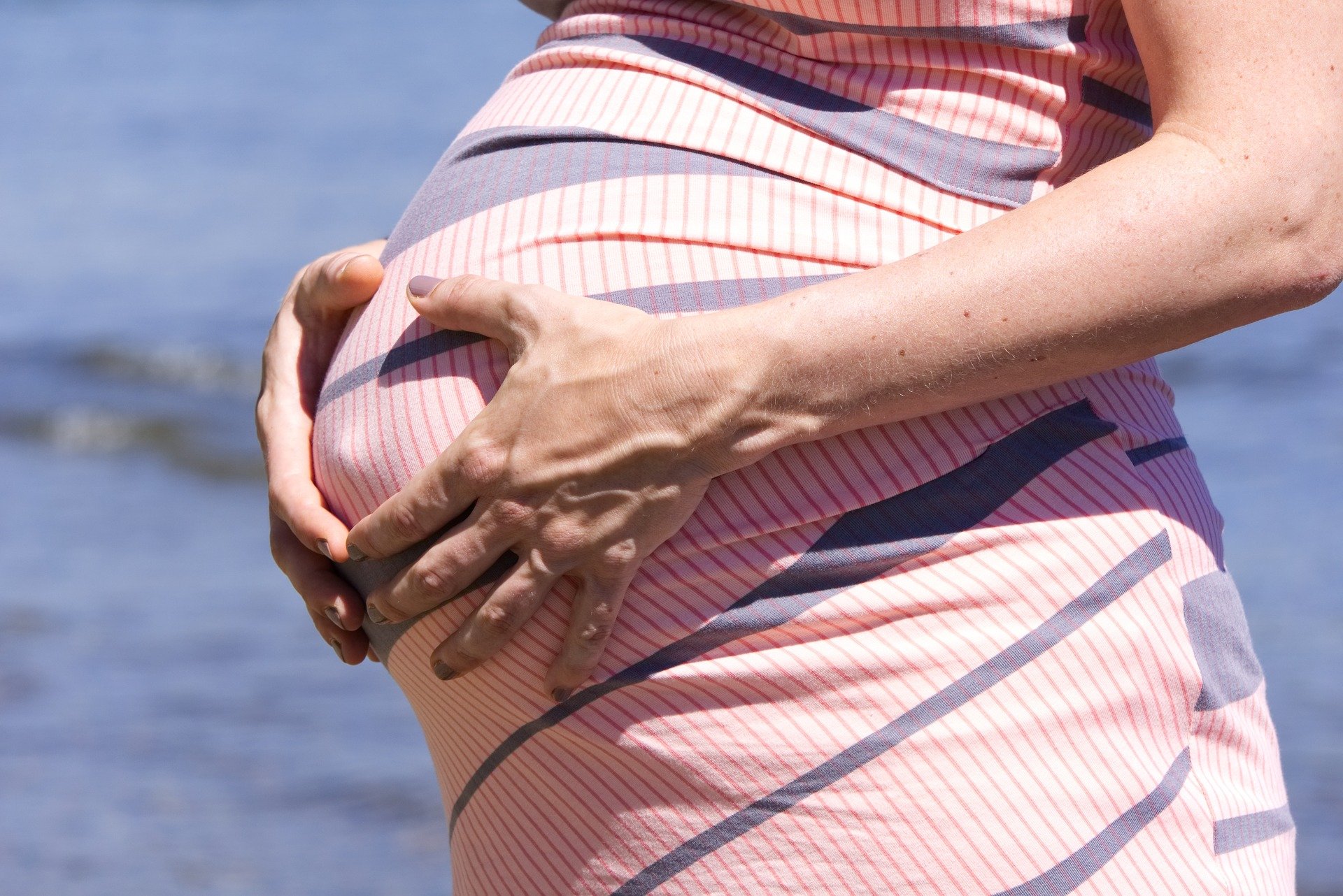 Mulher grávida com as mãos na barriga