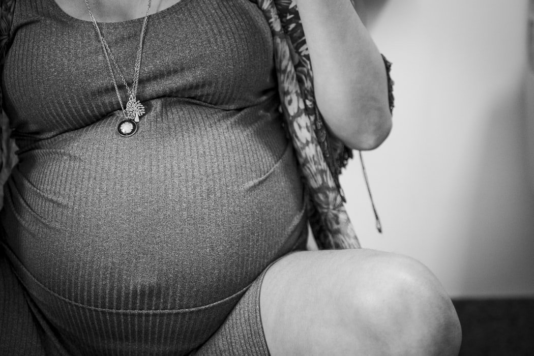 Thandy Yung/ Unsplash Foto preta e branca de close de barriga de grávida
