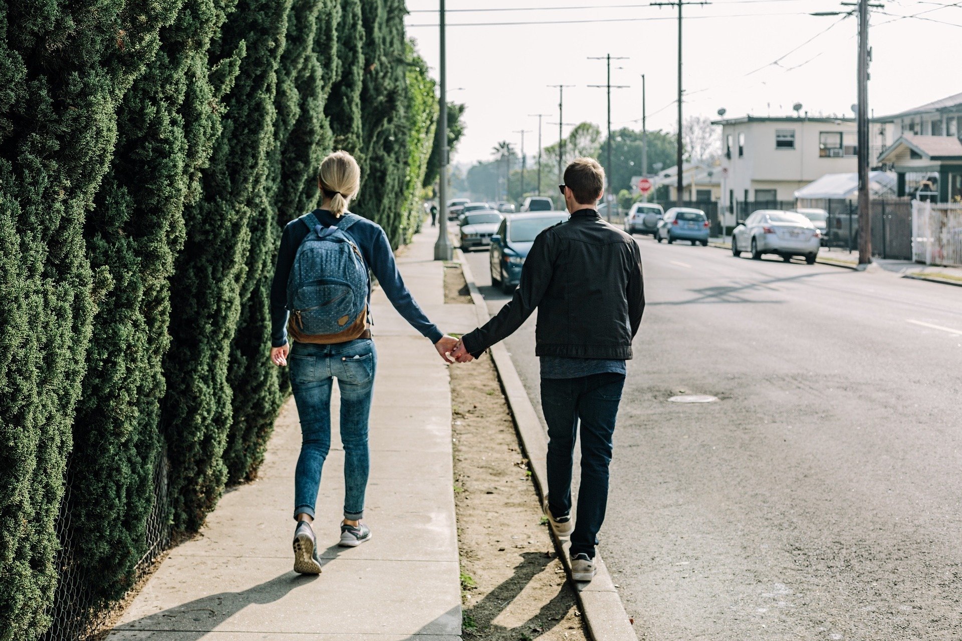 Casal caminhando de mãos dadas em calçada e rua
