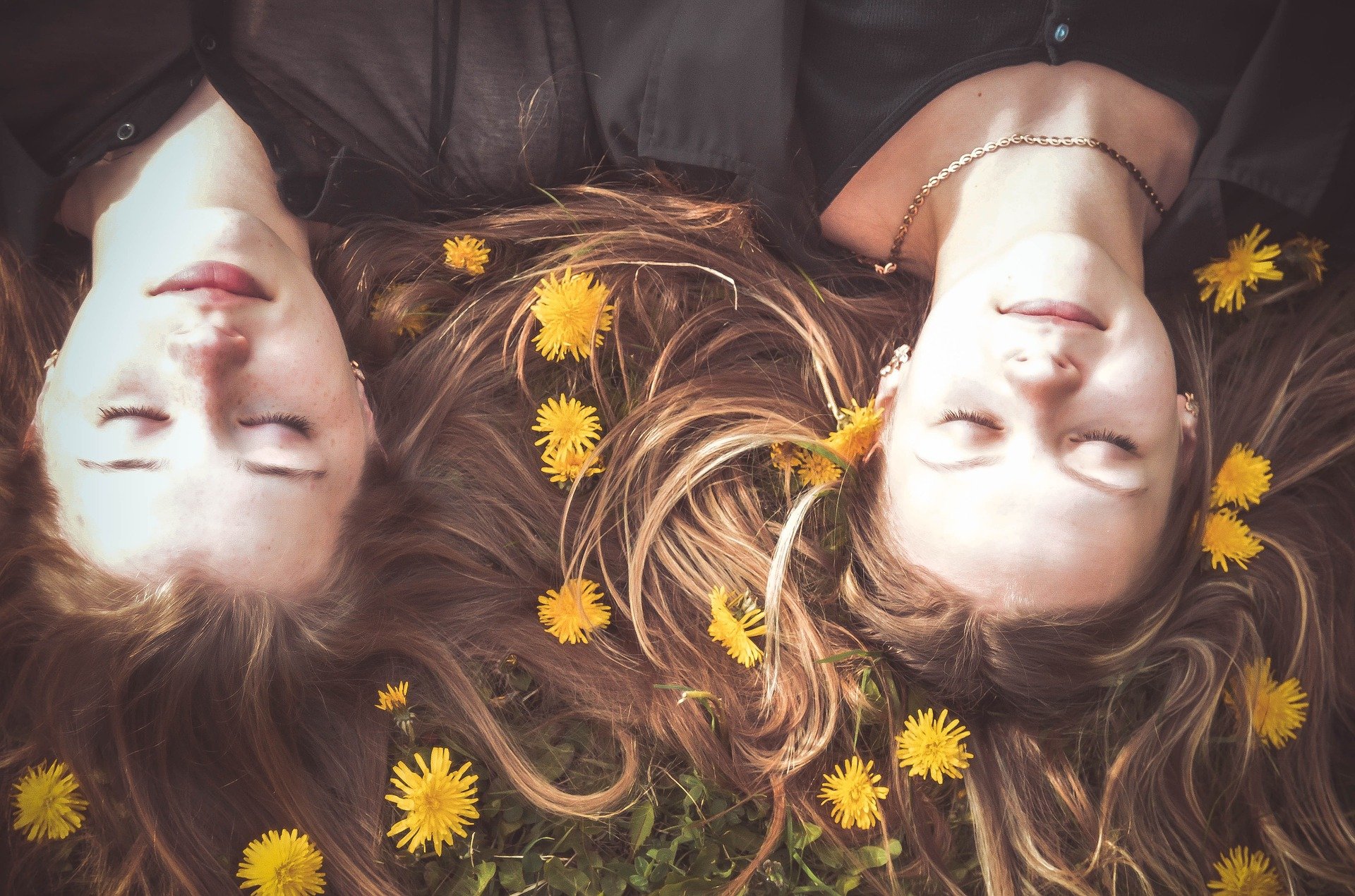Mulheres deitadas em campo com os olhos fechados com flores no cabelo