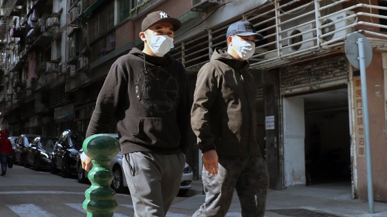 Dois homens andando na rua usando máscara no rosto