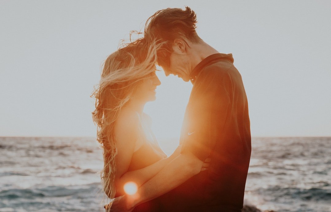 Homem e mulher se abraçando durante pôr do sol