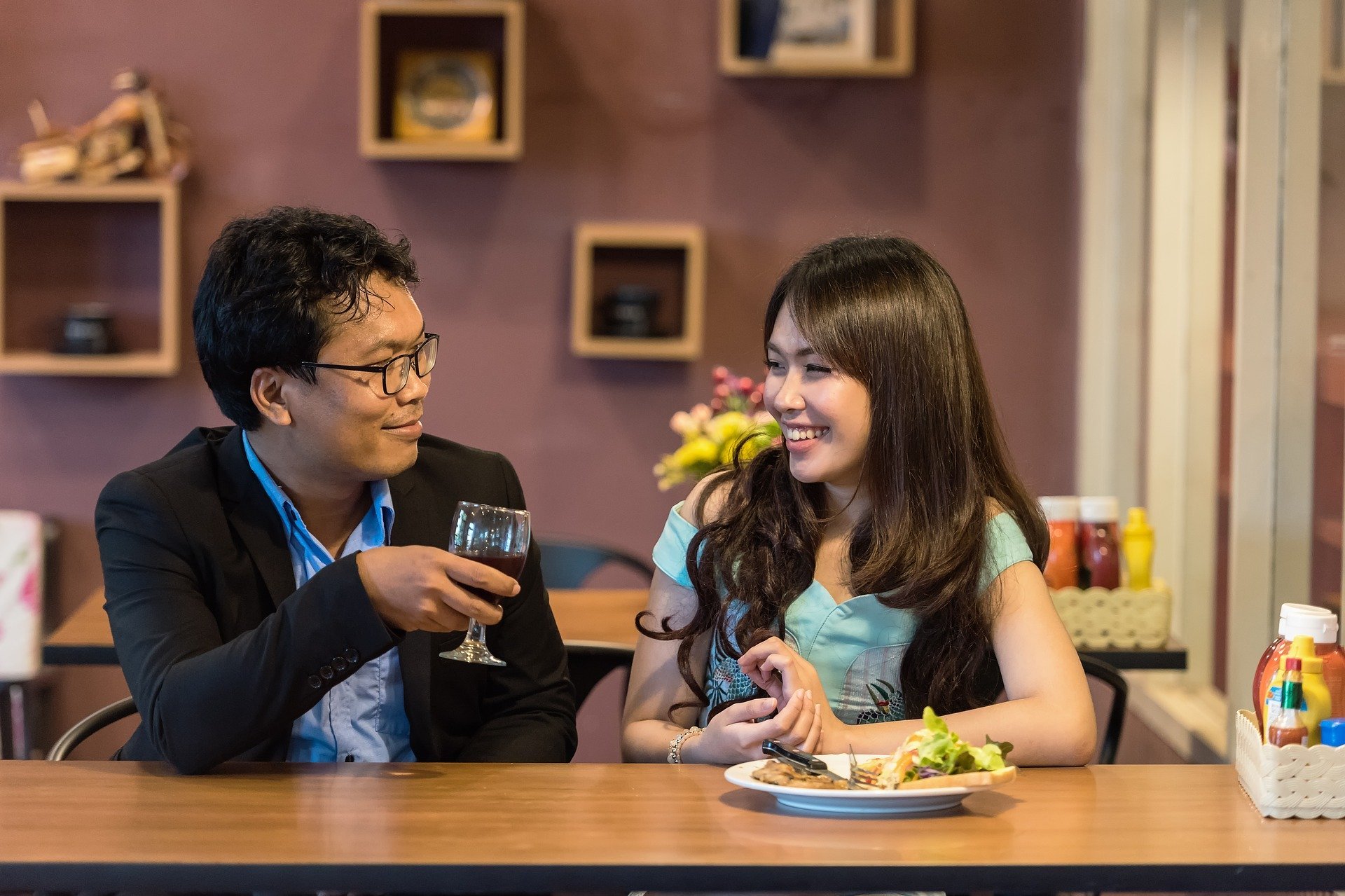 Homem e mulher sorrindo conversando enquanto comem e bebem em restaurante