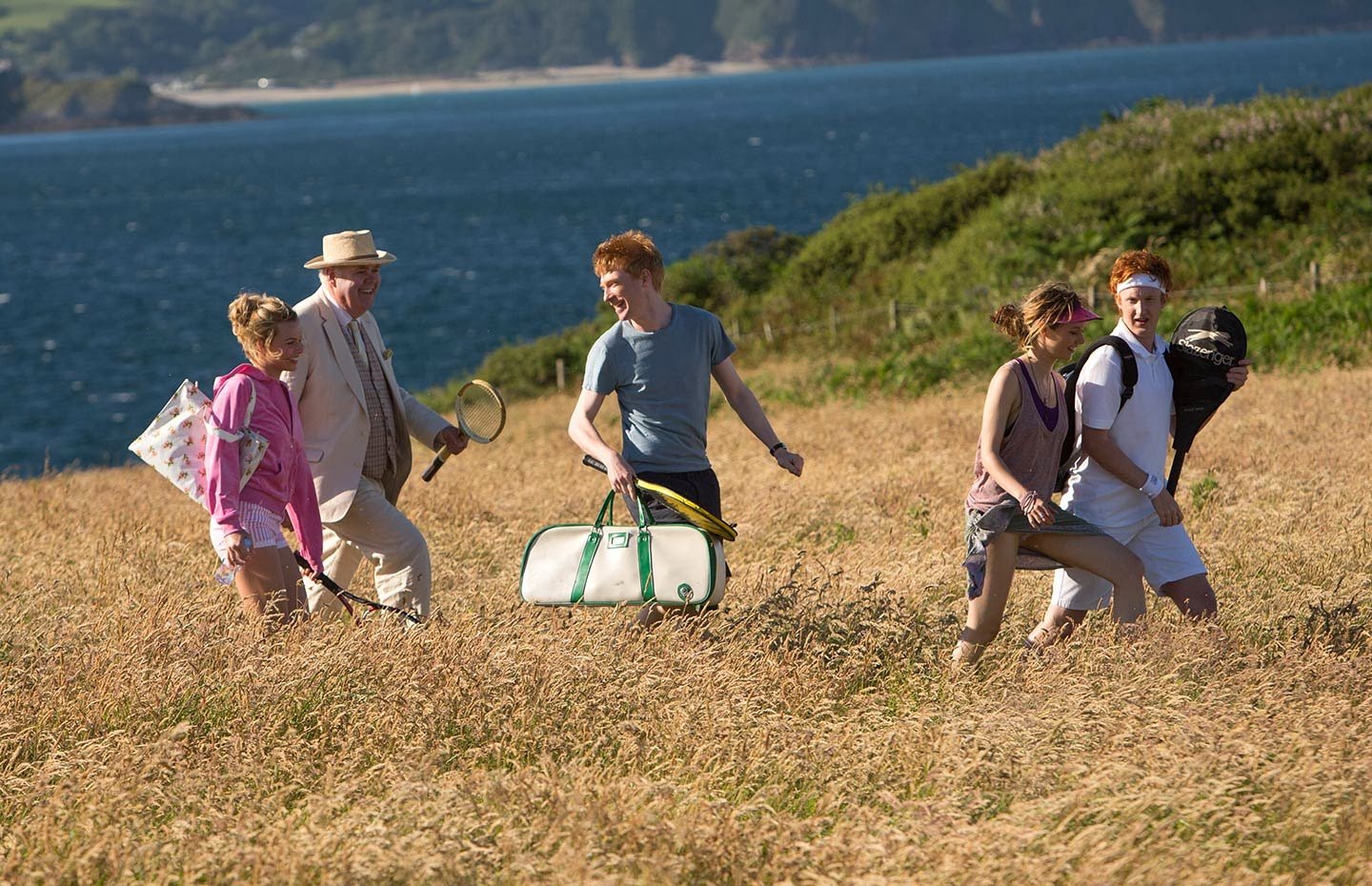 Personagens do filme Questão de Tempo correndo em campo de vegetação em dia ensolarado